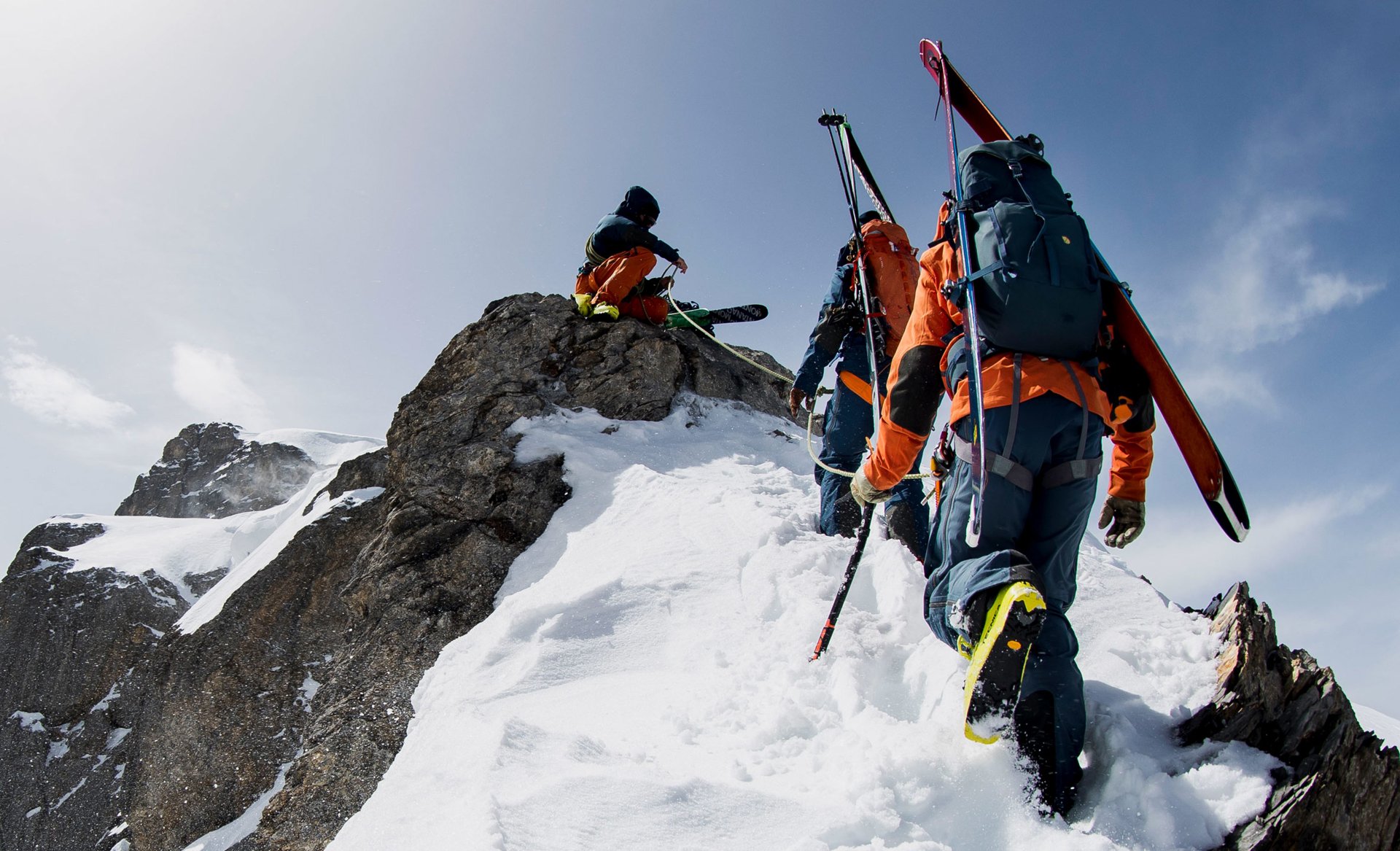 Three people sumitting a mountain with ski gear