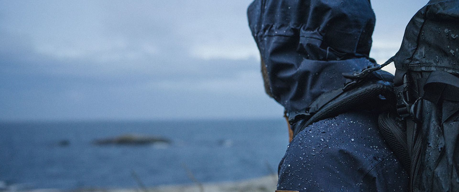 Man overlooking water with jacket repelling water droplets